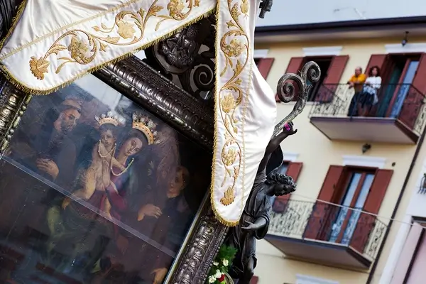 Detail of the miraculous painting of Our Lady of Consolation carried on the Vara during the Festa della Madonna della Consolazione in Reggio Calabria, with faithful participants in the procession toward the Duomo.