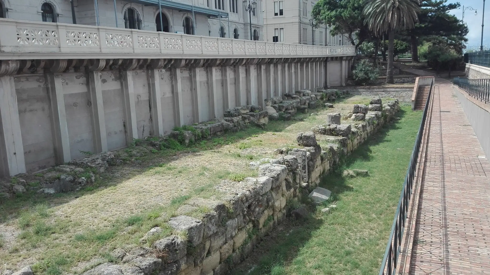 Section of the Greek Walls of Reggio Calabria along Lungomare Falcomatà, with sandstone blocks and iron fence.
