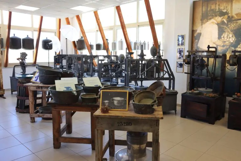 Exhibit room at the Museo del Bergamotto showing perfume bottles and traditional bergamot-processing machines.