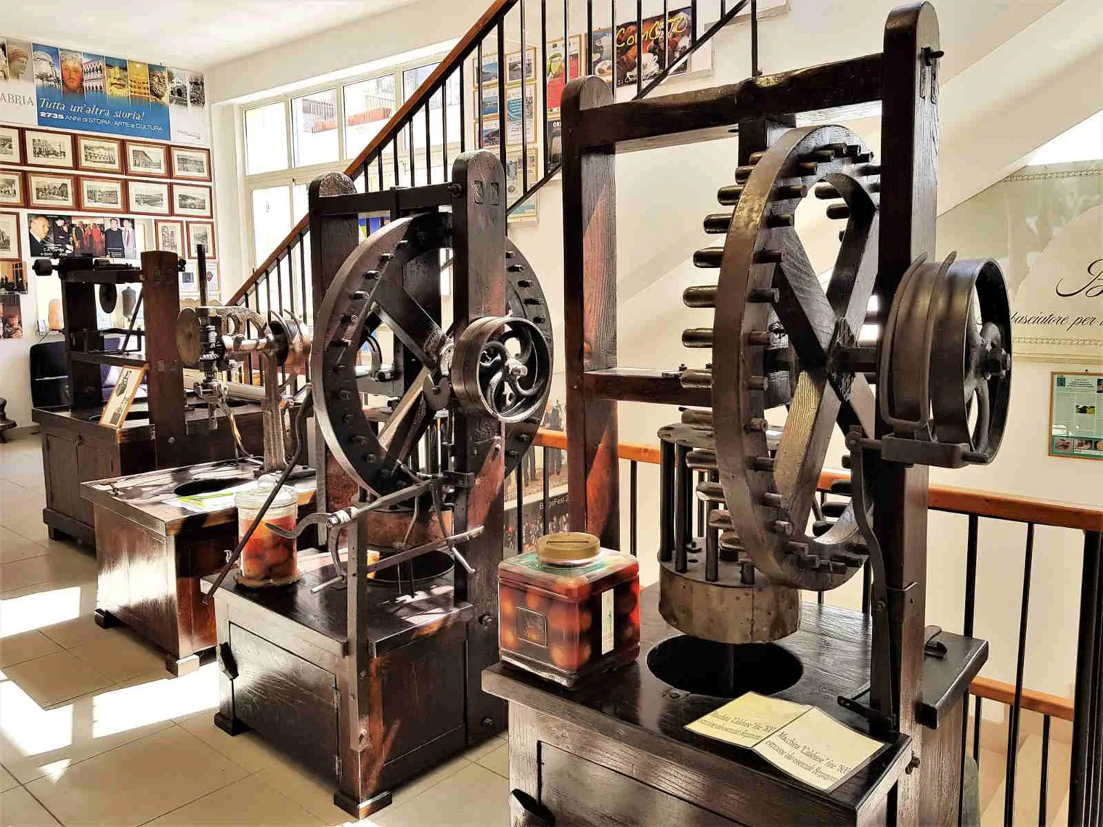 Exhibit room at the Museo del Bergamotto showing perfume bottles and traditional bergamot-processing machines.