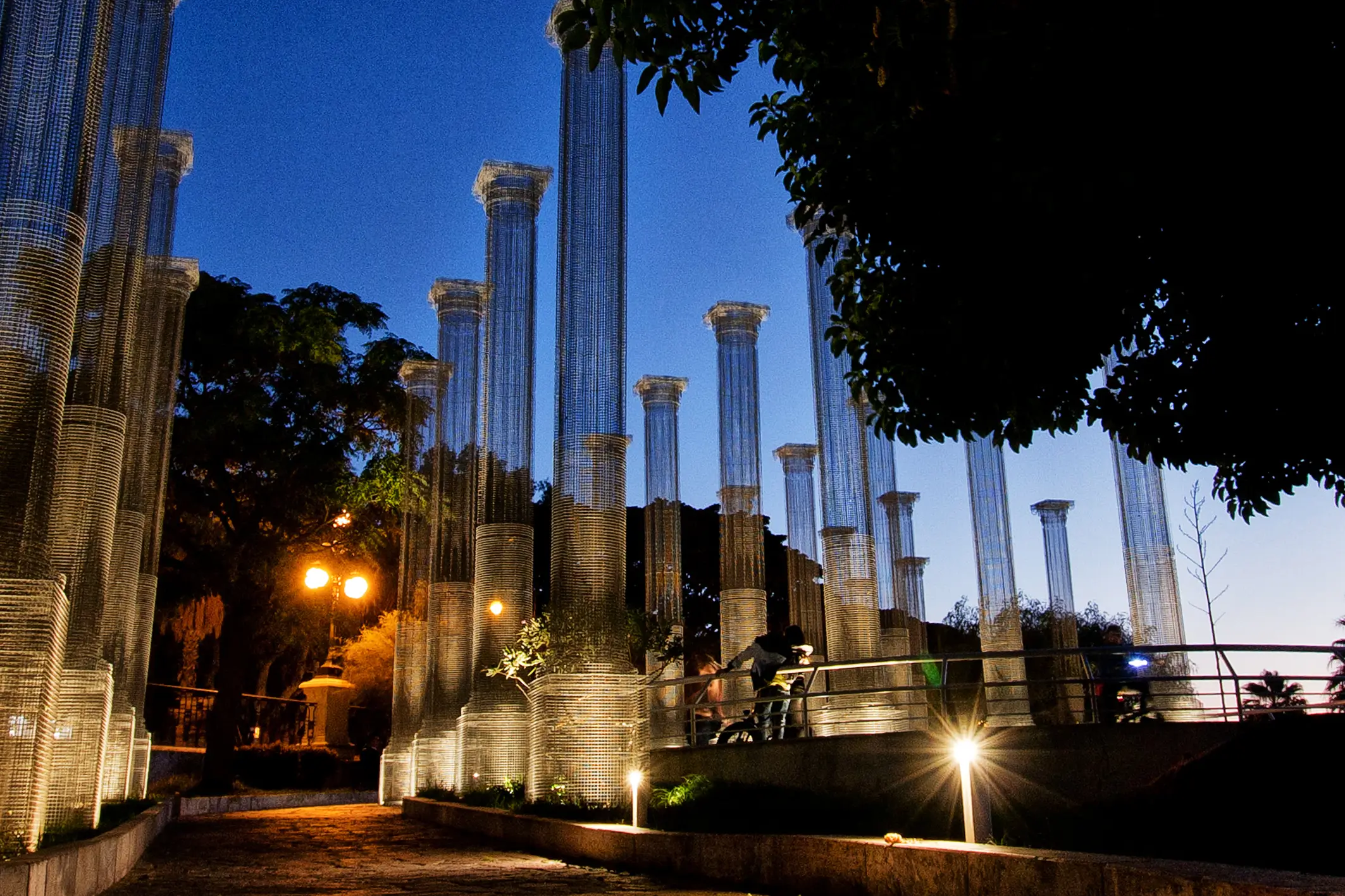 View of Opera, Edoardo Tresoldi’s metal mesh column installation, illuminated along Reggio Calabria’s Falcomatà waterfront.