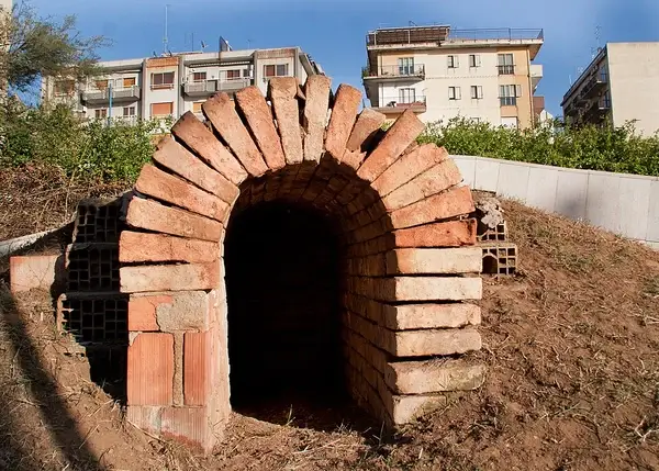 Interior and artifacts of the Hellenistic Monumental Tomb of Reggio Calabria, featuring the chamber structure and miniature Corinthian capitals.